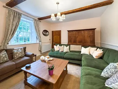 a living room with a green couch and a table at Manor Farmhouse in Church Stretton