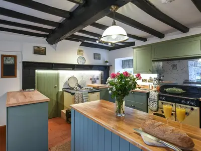 a kitchen with green cabinets and a vase of flowers on a counter at Manor Farmhouse in Church Stretton