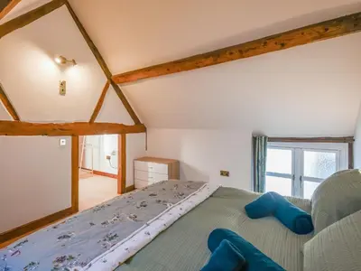 a bedroom with a bed with blue pillows on it at The Byre At Woodgate Farm in Church Stretton