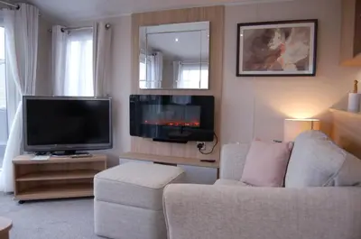 a living room with a couch and a flat screen tv at Seaview Caravan f17 at Neptune Park, Tywyn in Tywyn