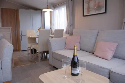 a living room with a couch and wine glasses on a table at Seaview Caravan f17 at Neptune Park, Tywyn in Tywyn