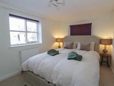 a bedroom with a bed with two green towels on it at Cariad Cottage in Hereford