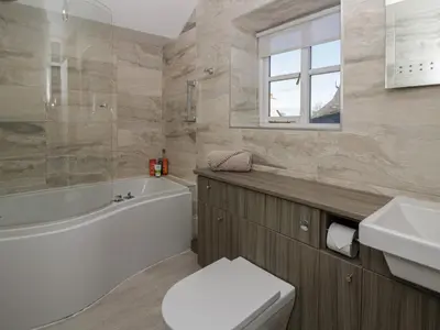 a bathroom with a tub and a toilet and a sink at Cariad Cottage in Hereford