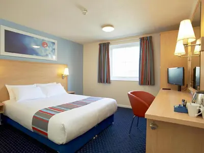 a hotel room with a bed and a desk with a computer at Travelodge Ludlow in Ludlow