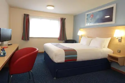 a hotel room with a bed and a desk and a television at Travelodge Ludlow in Ludlow