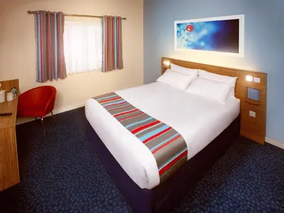 a hotel room with a bed and a red chair at Travelodge Ludlow Woofferton in Brimfield