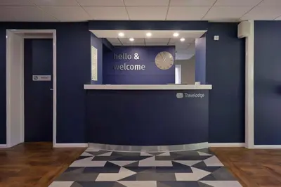 a lobby with a blue wall and a clock on the wall at Travelodge Oswestry in Oswestry