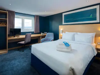 a hotel room with a large bed and a desk at Travelodge Shrewsbury Bayston Hill in Meole Brace