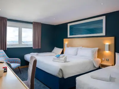 a hotel room with two beds and a desk at Travelodge Shrewsbury Bayston Hill in Meole Brace