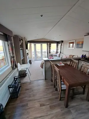 a kitchen and dining room with a wooden table and chairs at Sea and Bay Viev Luxury Lodge in Clarach bay in Aberystwyth
