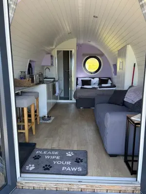 a living room with a couch and a kitchen at Four Paws Glamping in Aberystwyth