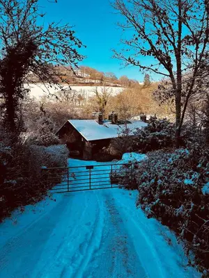 a snow covered road with a house and a fence at Pont Wrysgen Cottage 'the gateway to Snowdonia' in Mallwyd