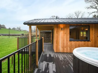 a wooden house with a hot tub on a deck at Lakeside Lodge - Uk50627 in Welshpool
