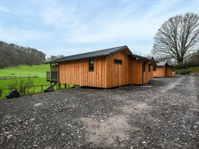 a row of wooden buildings on a gravel road at Lakeside Lodge - Uk50627 in Welshpool