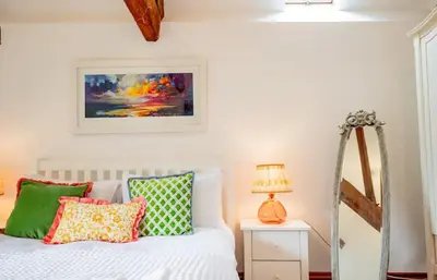 a bedroom with a bed with colorful pillows and a mirror at 5 bedroom Barn, Ludlow in Caynham
