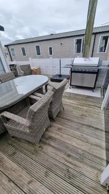 a patio with a table and chairs and a grill at Privately owned Pet friendly caravan in Llanddwywe