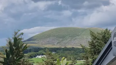 a green hill in the middle of a field at Privately owned Pet friendly caravan in Llanddwywe