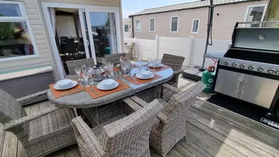 a table and chairs on a patio with a grill at Privately owned Pet friendly caravan in Llanddwywe