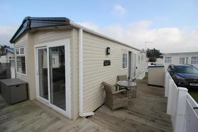 a mobile home with a porch and a table on a deck at Privately owned Pet friendly caravan in Llanddwywe