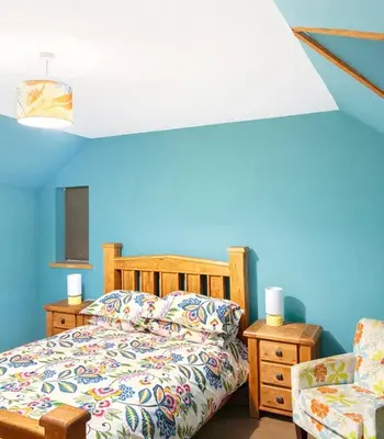a bedroom with a bed and a blue wall at Ferndale Cottage in Church Stretton