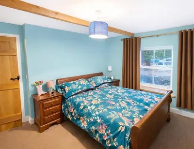 a bedroom with a bed with blue walls and a window at Ferndale Cottage in Church Stretton
