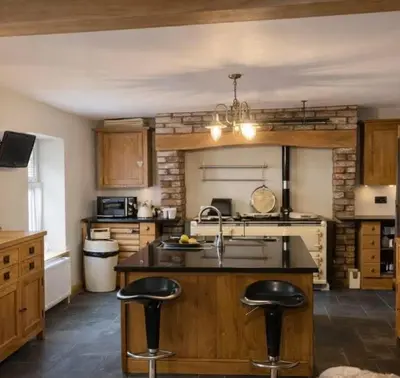 a kitchen with a sink and two bar stools at Ferndale Cottage in Church Stretton