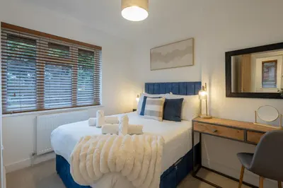 a bedroom with a large bed with a desk and windows at Judith House in Shrewsbury