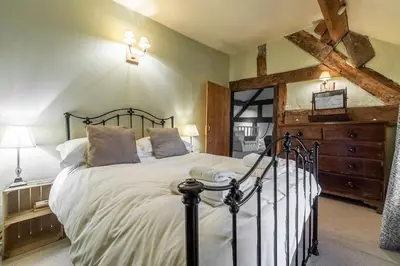 a bedroom with a large bed with white sheets at Tanat Valley Farmhouse in Hirnant