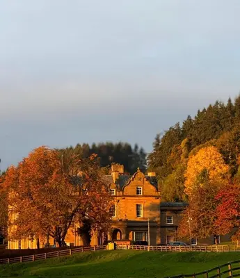 a large house in a field next to a fence at Baskerville Hall Hotel in Clyro