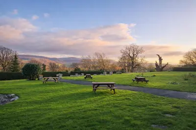 a group of benches sitting in a grass field at Baskerville Hall Hotel in Clyro