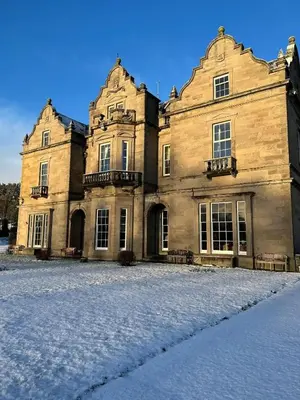 a large stone building with snow on the ground at Baskerville Hall Hotel in Clyro