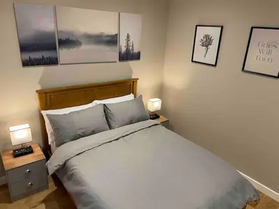 a bedroom with a bed with two night stands and two lamps at Luxury Lakeside Lodge with Hot Tub in Ratlinghope in Ratlinghope