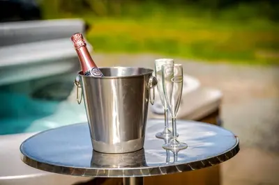 a metal bucket with a bottle and glasses on a table at Luxury Lakeside Lodge with Hot Tub in Ratlinghope in Ratlinghope