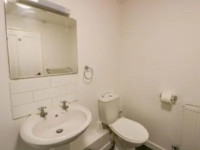 a white bathroom with a toilet and a sink at The Old Sunday School in Brecon