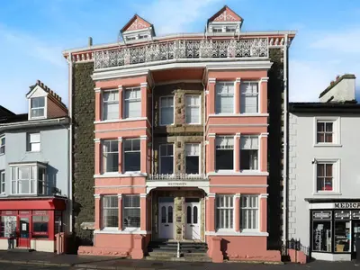 a pink building with a balcony on top of it at Westhaven Five in Aberdyfi