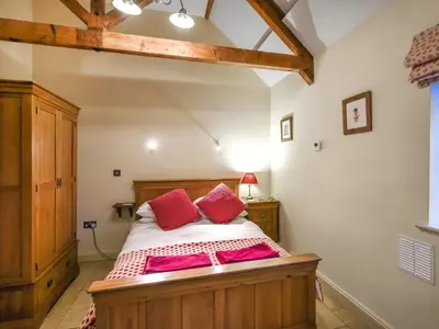 a bedroom with a bed with red pillows on it at Lower House Barn in Staunton on Wye