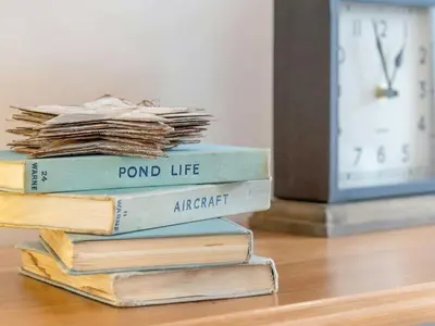 a stack of books sitting on a table next to a clock at Seagrass Cottage in Aberdyfi