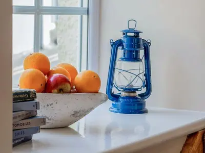 a blue lantern and a bowl of fruit on a table at Seagrass Cottage in Aberdyfi