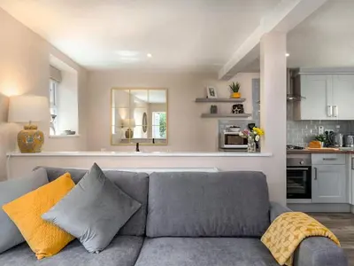 a living room with a gray couch and a kitchen at Seagrass Cottage in Aberdyfi