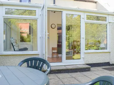a glass door of a house with a table and chairs at Canon's Cottage in Clun