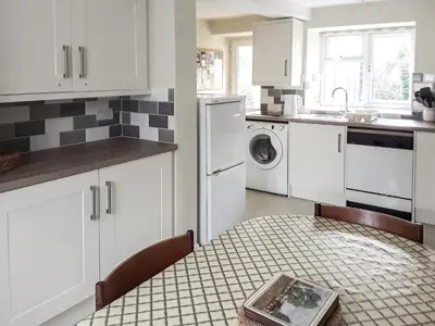 a kitchen with white cabinets and a table with a plate on it at Canon's Cottage in Clun