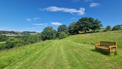 a bench sitting on top of a grassy hill at Oak Hill Escape in Welshpool