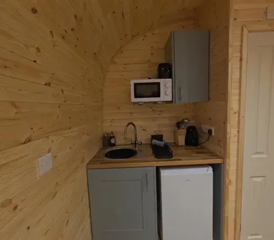 a small kitchen with a sink and a microwave at Salt Marsh Cabin - Hot tub-Sauna in Barmouth