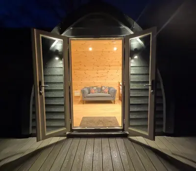 a room with a couch through an open door at Salt Marsh Cabin - Hot tub-Sauna in Barmouth