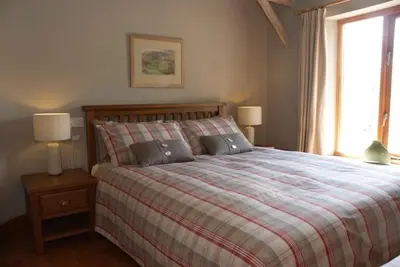 a bedroom with a bed with two lamps and a window at Alder Barn in Clun