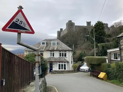 a road sign in front of a house with a castle at Harlech castle and beach home in Harlech