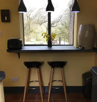 a kitchen counter with two stools under a window at Off Grid living high in the hills in Picklescott