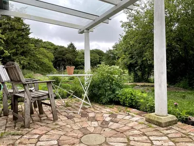 a patio with a table and a bench and a pergola at Off Grid living high in the hills in Picklescott