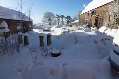 a yard covered in snow next to a building at Off Grid living high in the hills in Picklescott