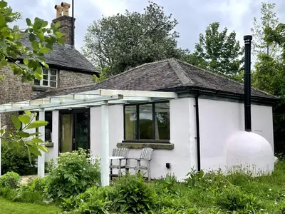 a white house with two chairs in front of it at Off Grid living high in the hills in Picklescott